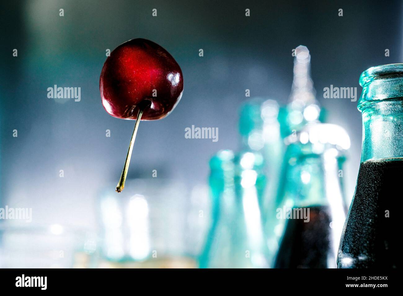 Wie ein Ballon, umgeben von Cola-Flaschen, schwebt die Kirsche durch die Luft Stockfoto