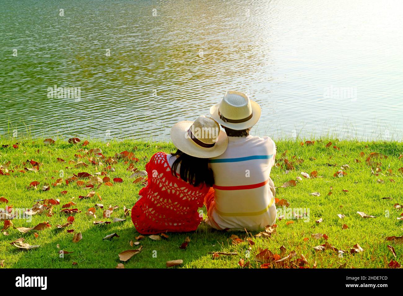 Ein Paar im Strohhut, das sich am See entspannt Stockfoto