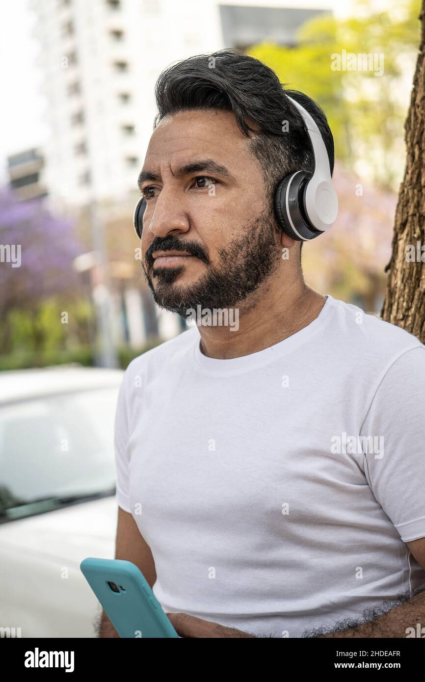 Porträt eines bärtigen lateinmanns mit Kopfhörern in der Stadt Stockfoto