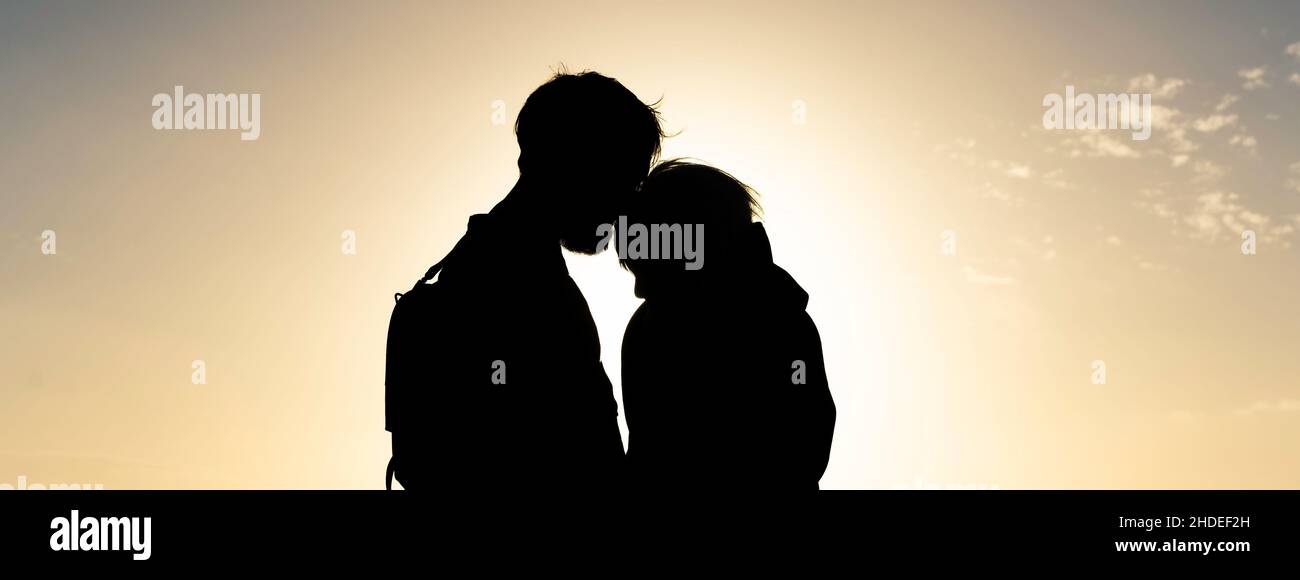 Horizontales Banner mit Silhouette eines jungen Hipster-Reisenden Paares, das einen Vintage-Rucksack trägt und beim wunderschönen Sonnenuntergang steht - Love Concept und -out Stockfoto