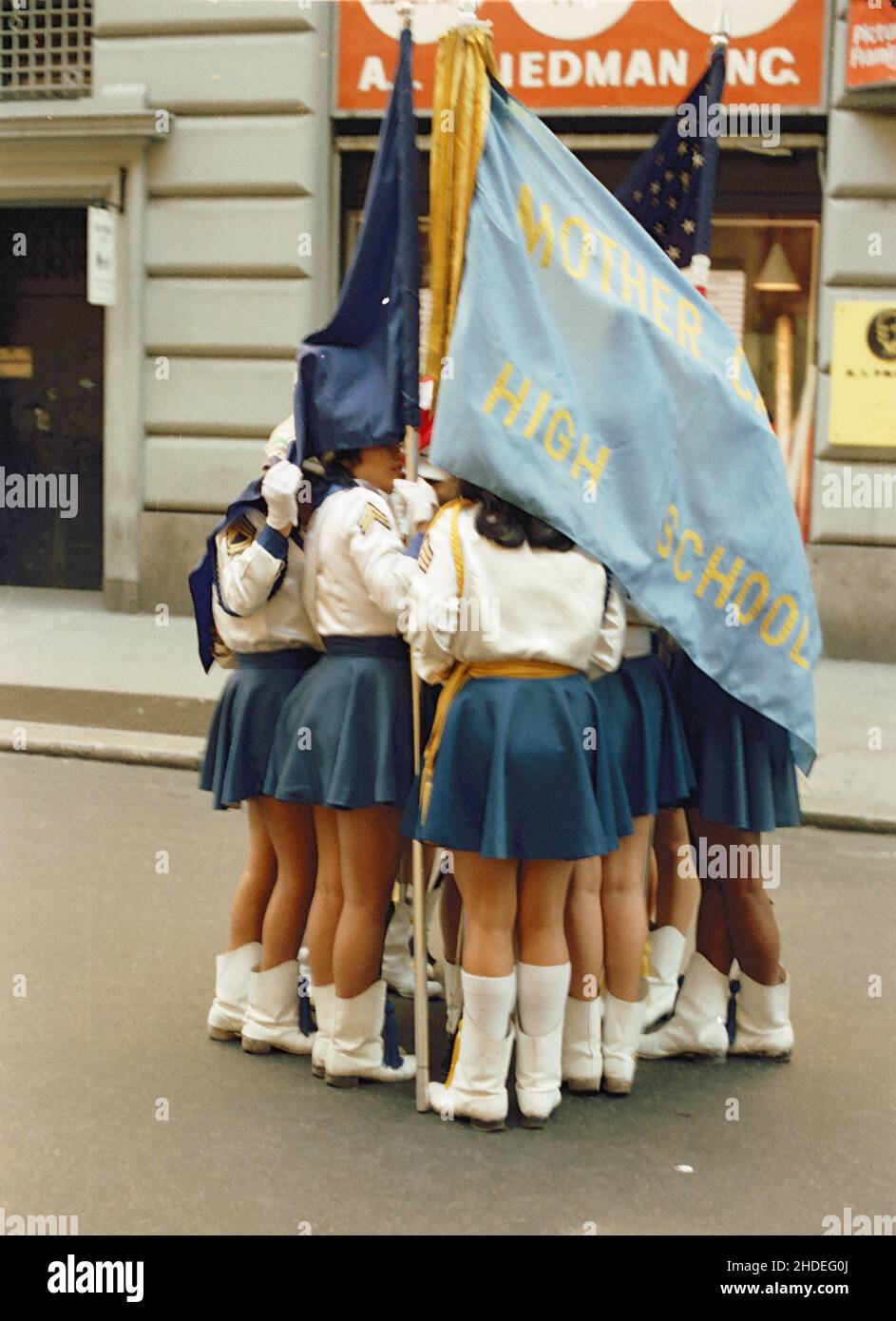 Eine Gruppe Studentinnen huddle unter der Flagge ihrer Schule vor der Columbus Day Parade in den frühen achtziger Jahren in New York, USA Stockfoto