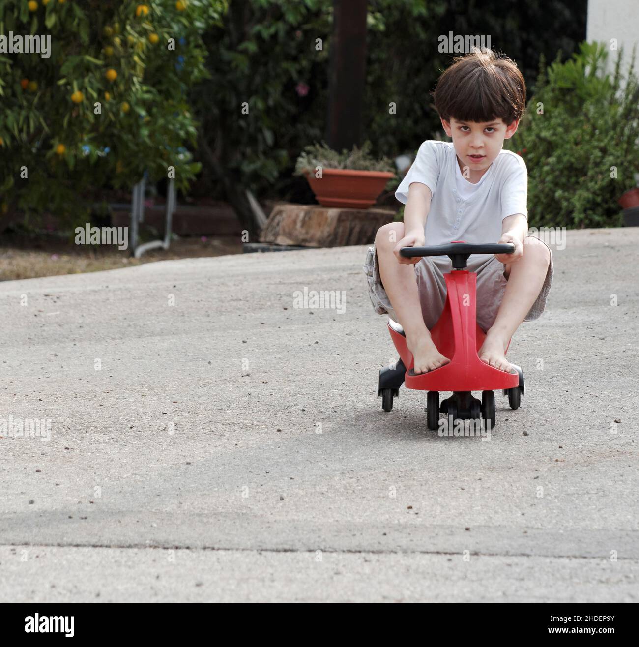 Kleiner Junge von sechs spielt draußen auf einem Spielzeugwagen Model Releases Stockfoto