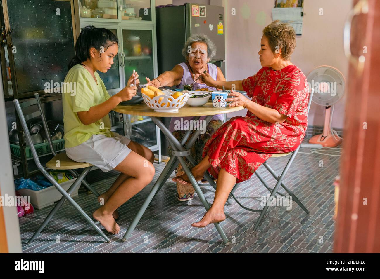Drei Generationen asiatischer Frauen sitzen zu Hause und essen gemeinsam zu Mittag. Familie von Großmutter, Tochter und Enkelin beim Frühstück Stockfoto