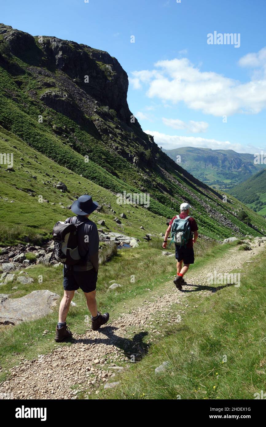 Two Men Walking by the Wainwright 'Eagle Crag' on the Coast to Coast Path (C2C) near Greenup Gill in Borrowdale, Lake District National Park. England. Stockfoto