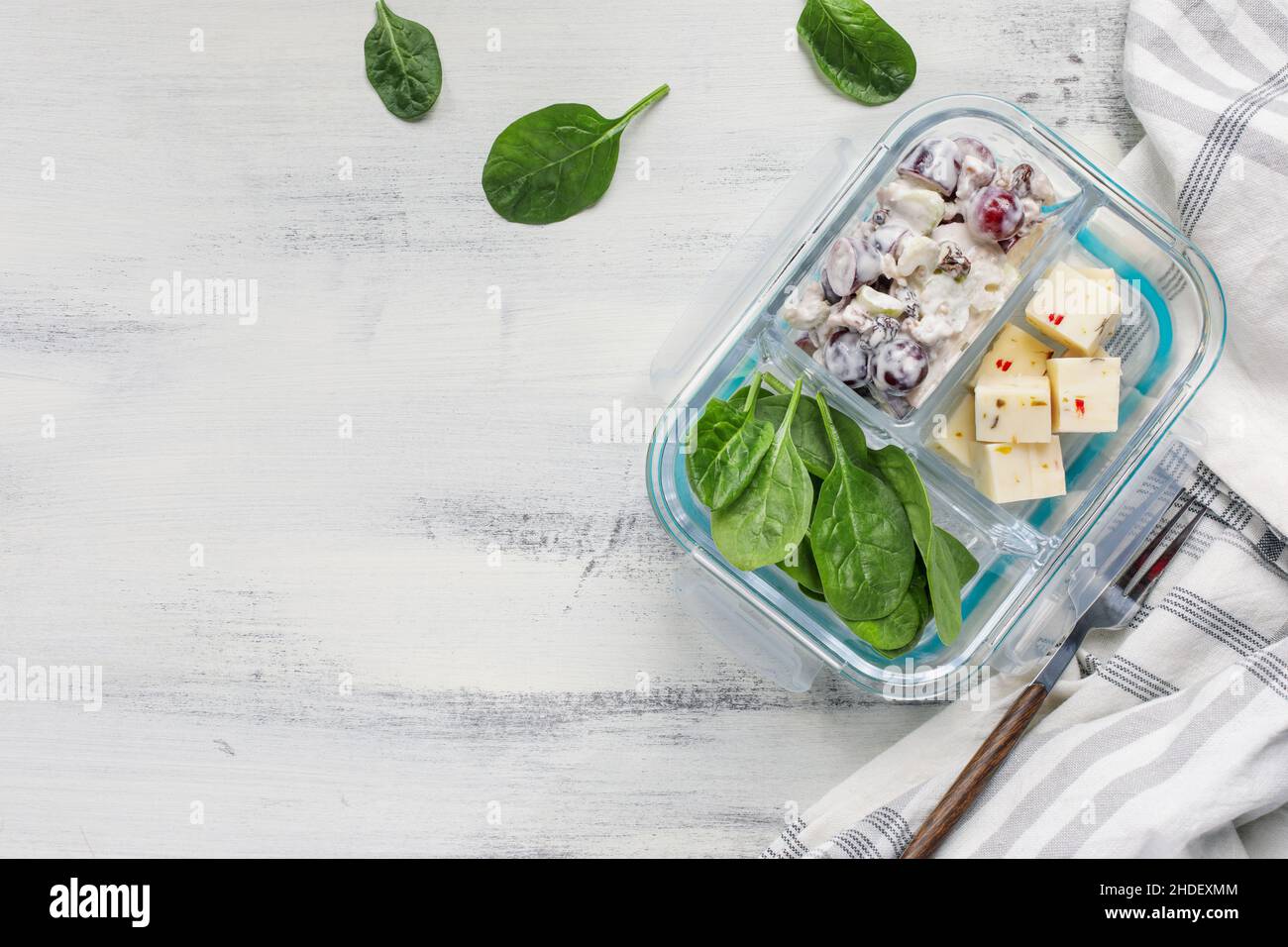 Lunchpaket mit waldorfsalat aus Apfelnuss und Spinat mit einem gewürfelten Käse in einem Glasbehälter. Gesunde vegetarische Ernährung. Stockfoto