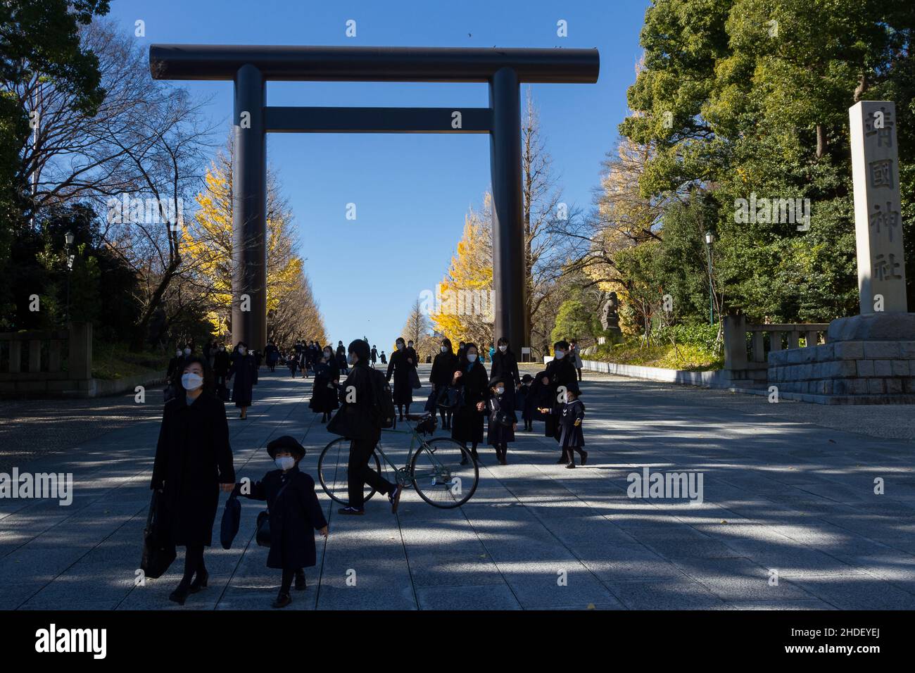 Mütter und Kindergartenkinder gehen unter dem großen eisernen Torii-Tor am umstrittenen Yasukuni-Schrein in Kudanshita, Tokio, Japan. Stockfoto