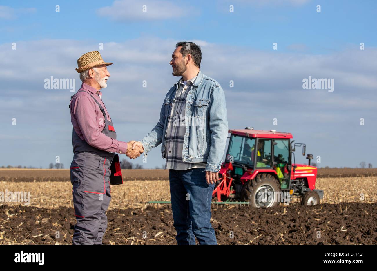 Glücklicher reifer Bauer kam zu einer Vereinbarung mit einem Besitzer auf bebautem Land. Stockfoto