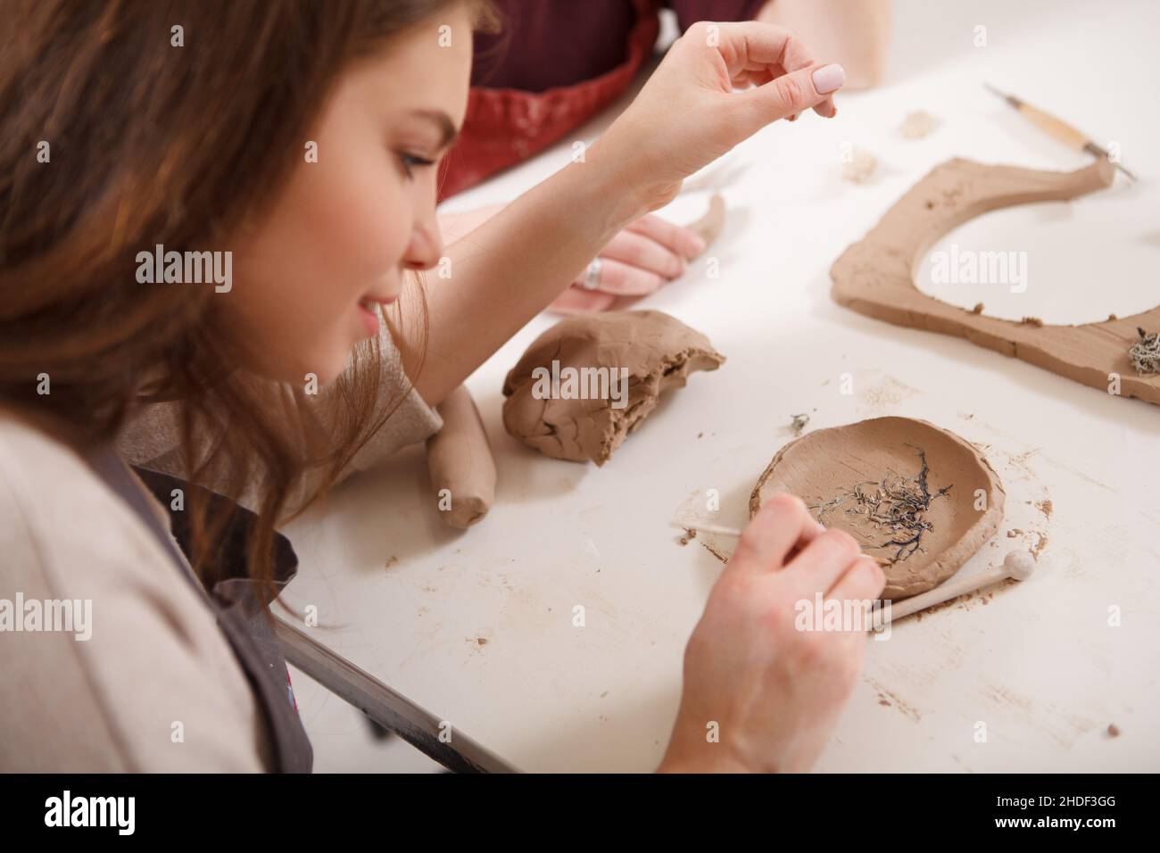 Nahaufnahme einer Frau, die in der Tonwerkstatt Keramikplatte macht Stockfoto