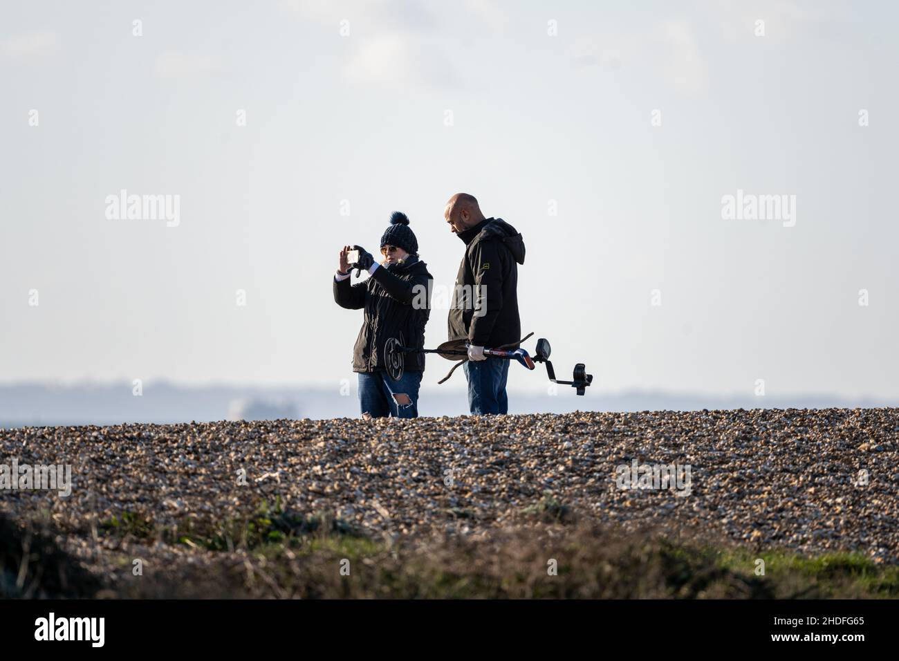 Detektorist. Ein Paar mit einem Metalldetektor am Strand von Hayling Island, Hampshire, Großbritannien Stockfoto