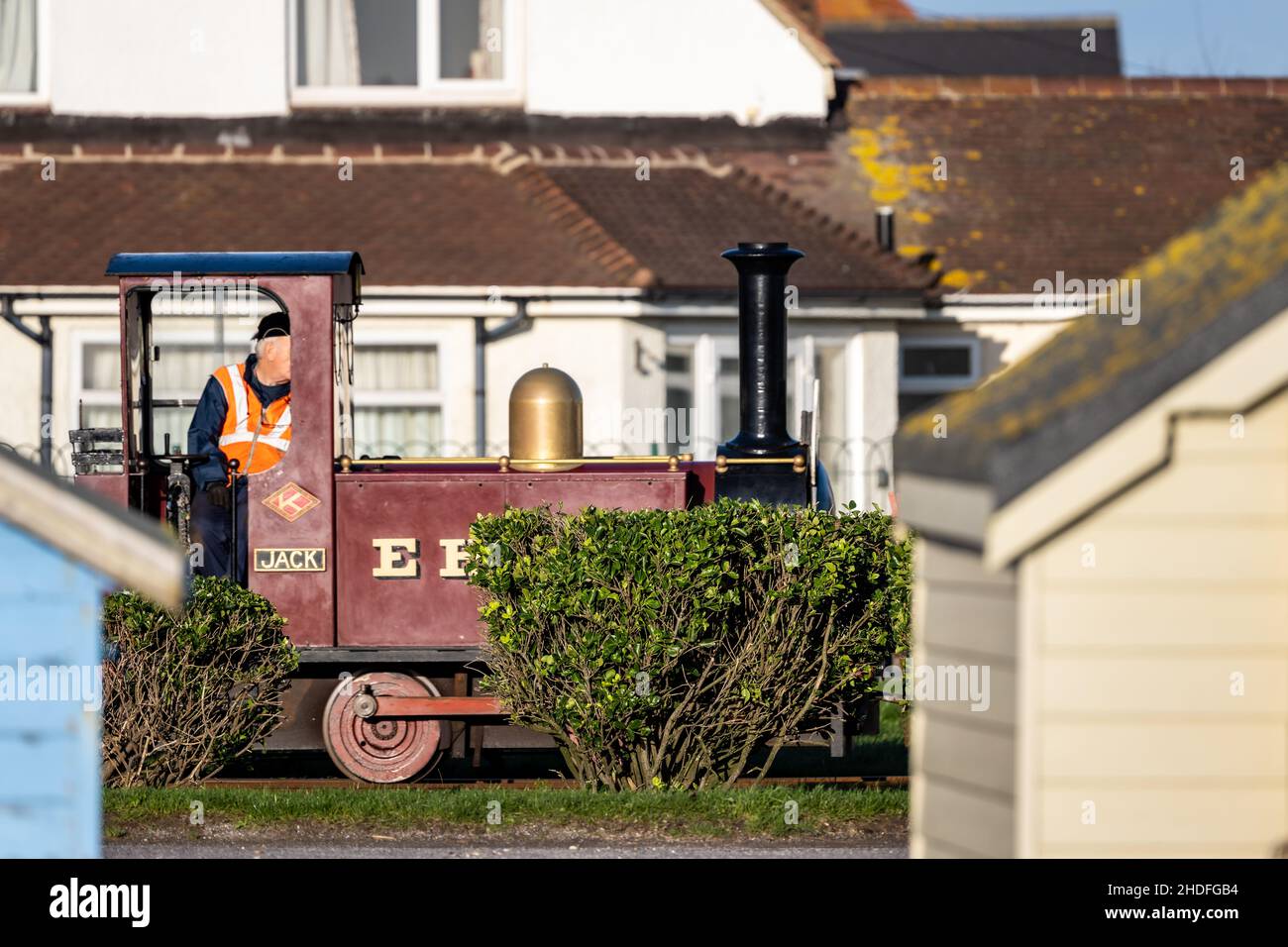 Der Lokführer fährt an Strandhütten auf der schmalen Hayling Seaside Railway, Hayling Island, Hampshire, Großbritannien Stockfoto