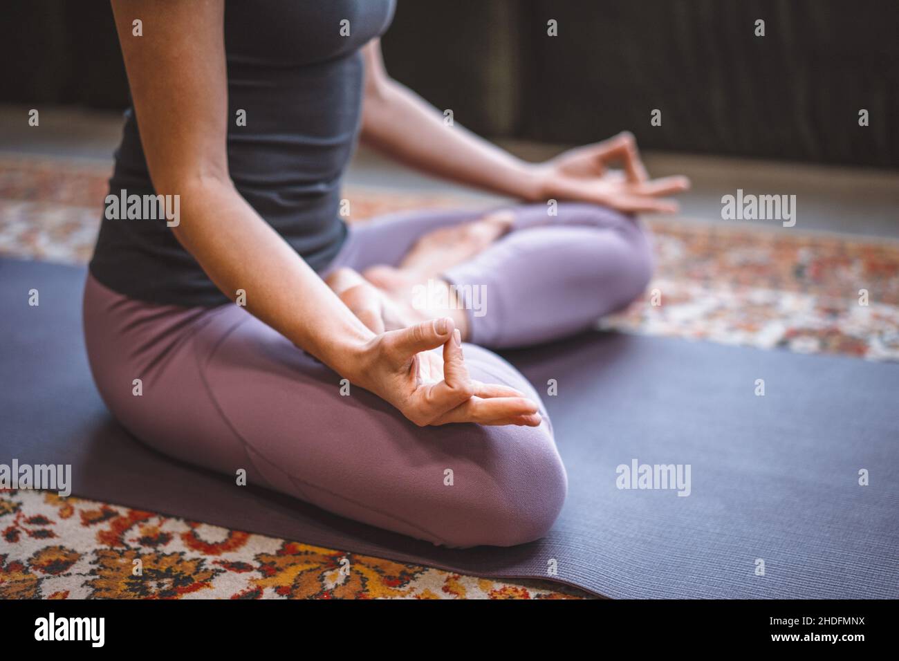 Concet Meditation. Frau, die in Lotus-Pose sitzt. Yoga-Frau praktiziert Yoga-Meditationsübung auf der Matte in ihrem Wohnzimmer zu Hause. Nahaufnahme. Hochwertige Fotos Stockfoto