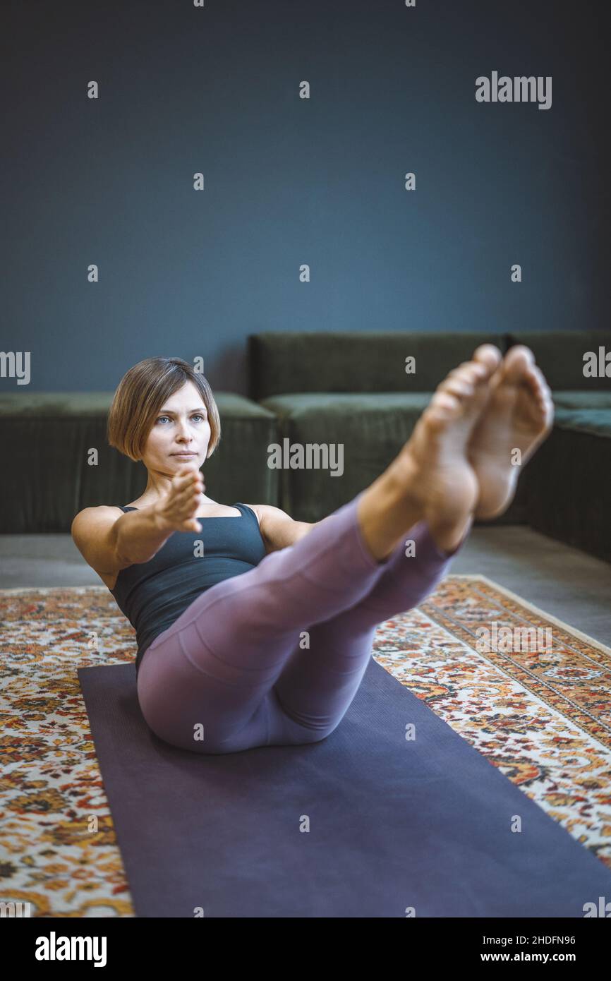 Paripurna Navasana Übung, Sport Workout Style, Fitness zu Hause, Gesunder Lebensstil. Yogi weiblich üben Boot Pose auf Matte im Wohnzimmer. Nahaufnahme. Hochwertige Fotos Stockfoto