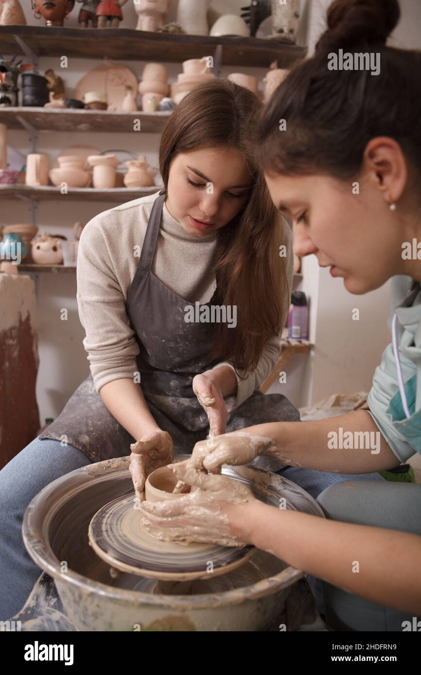 Vertikale Aufnahme eines professionellen Töpfers, der Frau bei der Arbeit am Töpferrad beibringt Stockfoto