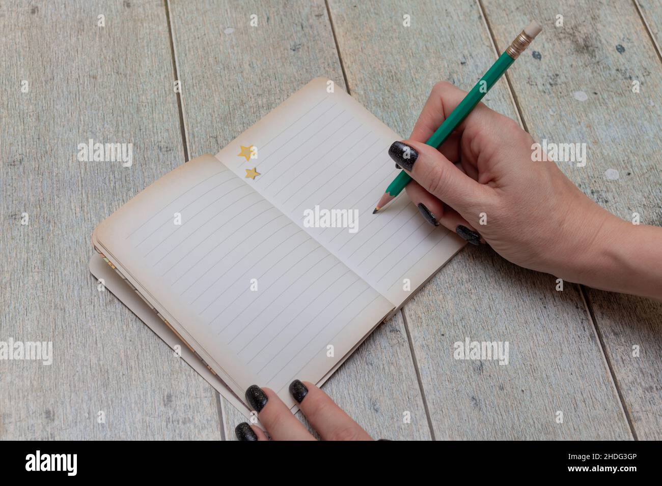 Weibliche Hand schreibt mit einem Bleistift in ein Notizbuch Stockfoto