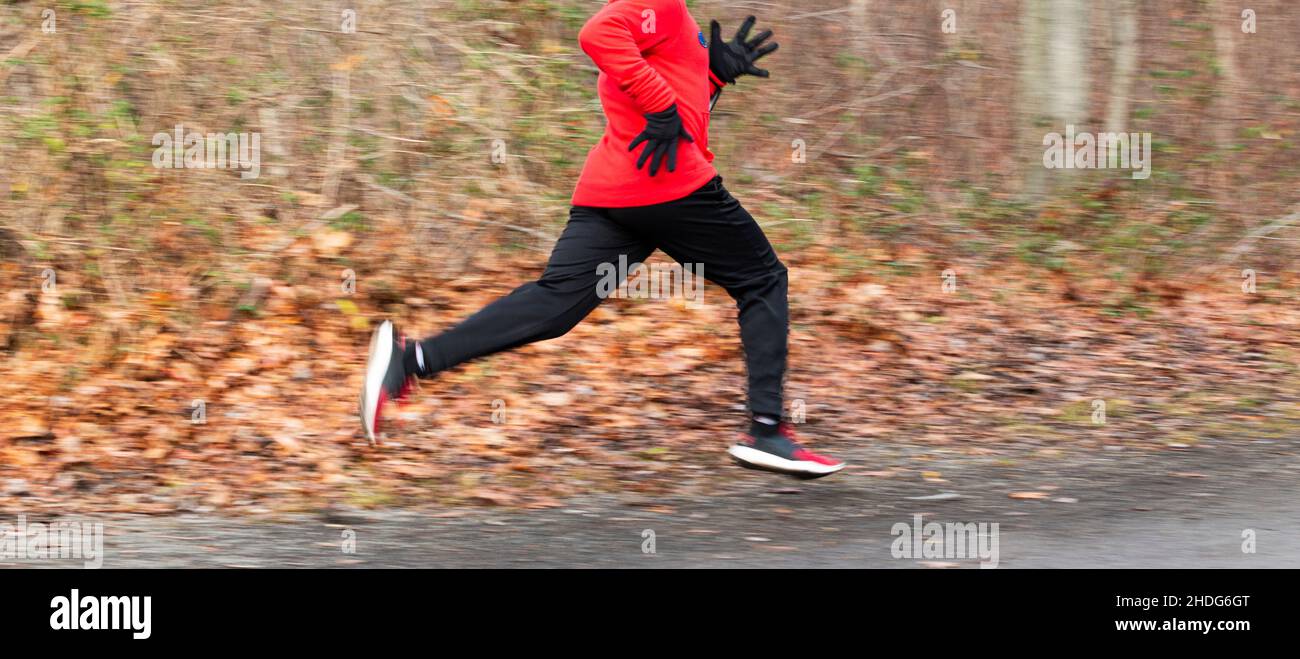 High School Junge läuft schnell im Wald um eine Ecke auf einem Feldweg im Wald. Stockfoto
