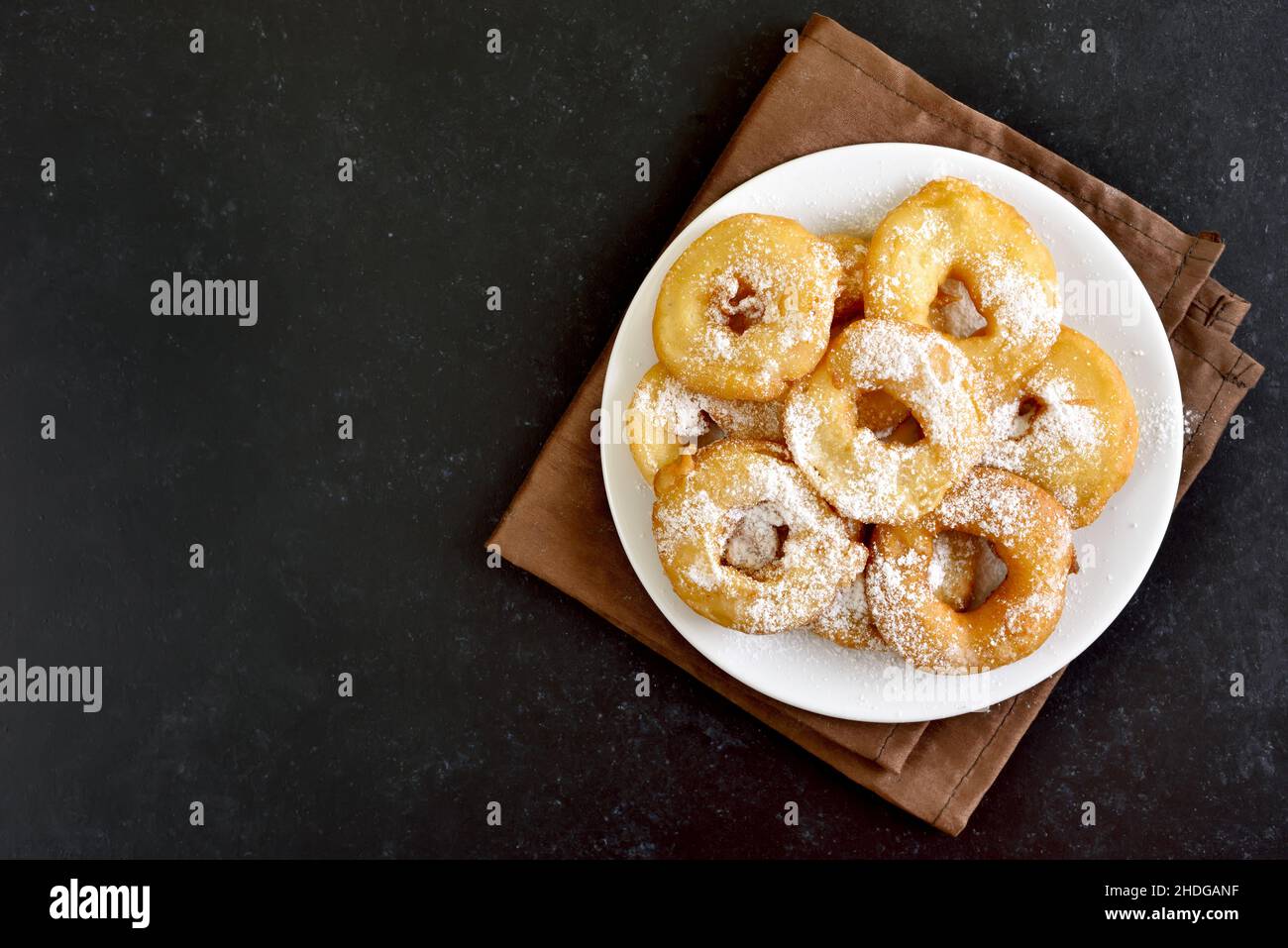 Hausgemachte Donuts auf weißem Teller über dunklem Steinhintergrund. Draufsicht, flach liegend Stockfoto