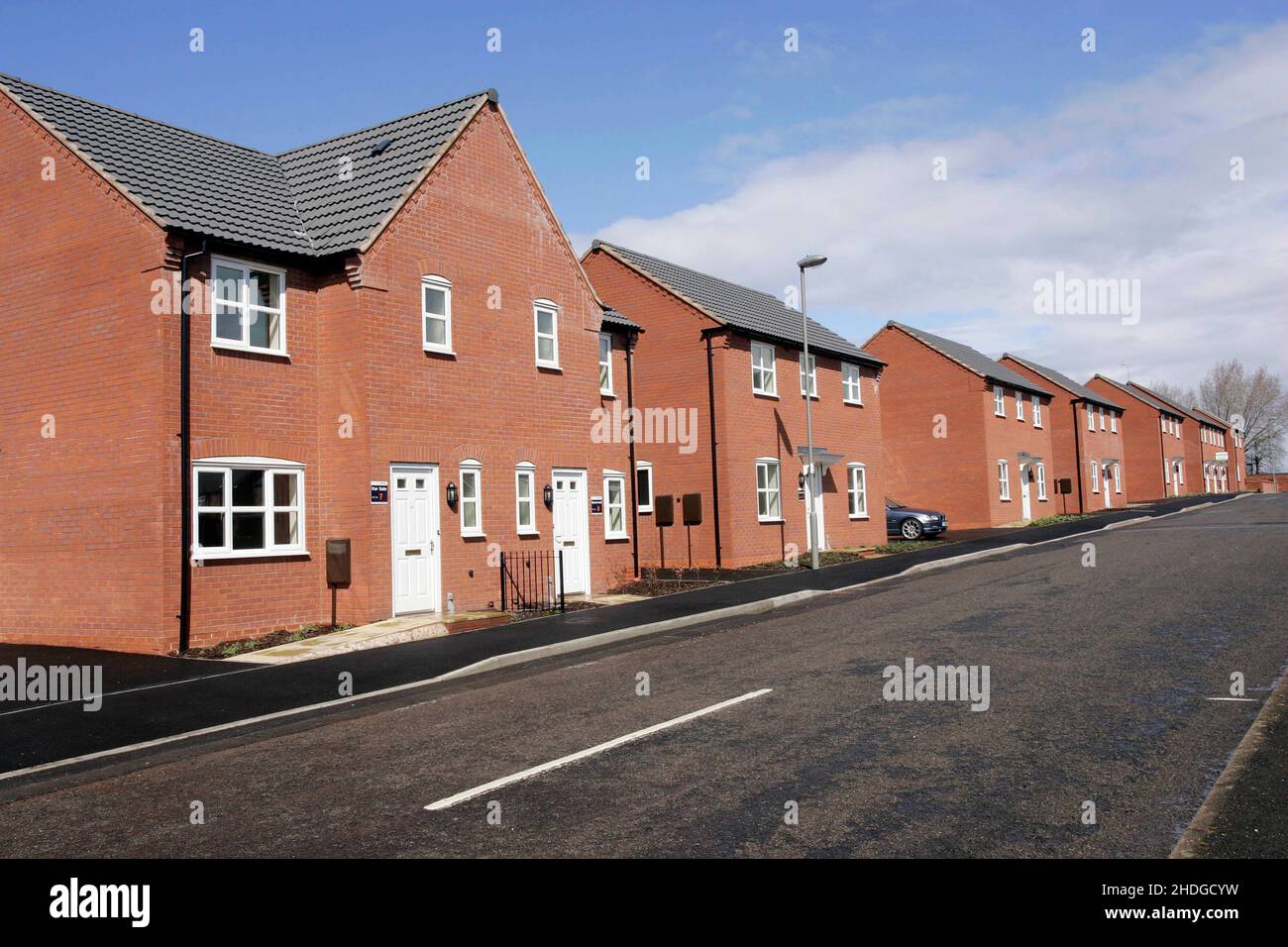 Reihe von Neubau-Gehäuse, freistehende und Doppelhaushälften, frische asphaltierte Straße, blauer Himmel Stockfoto
