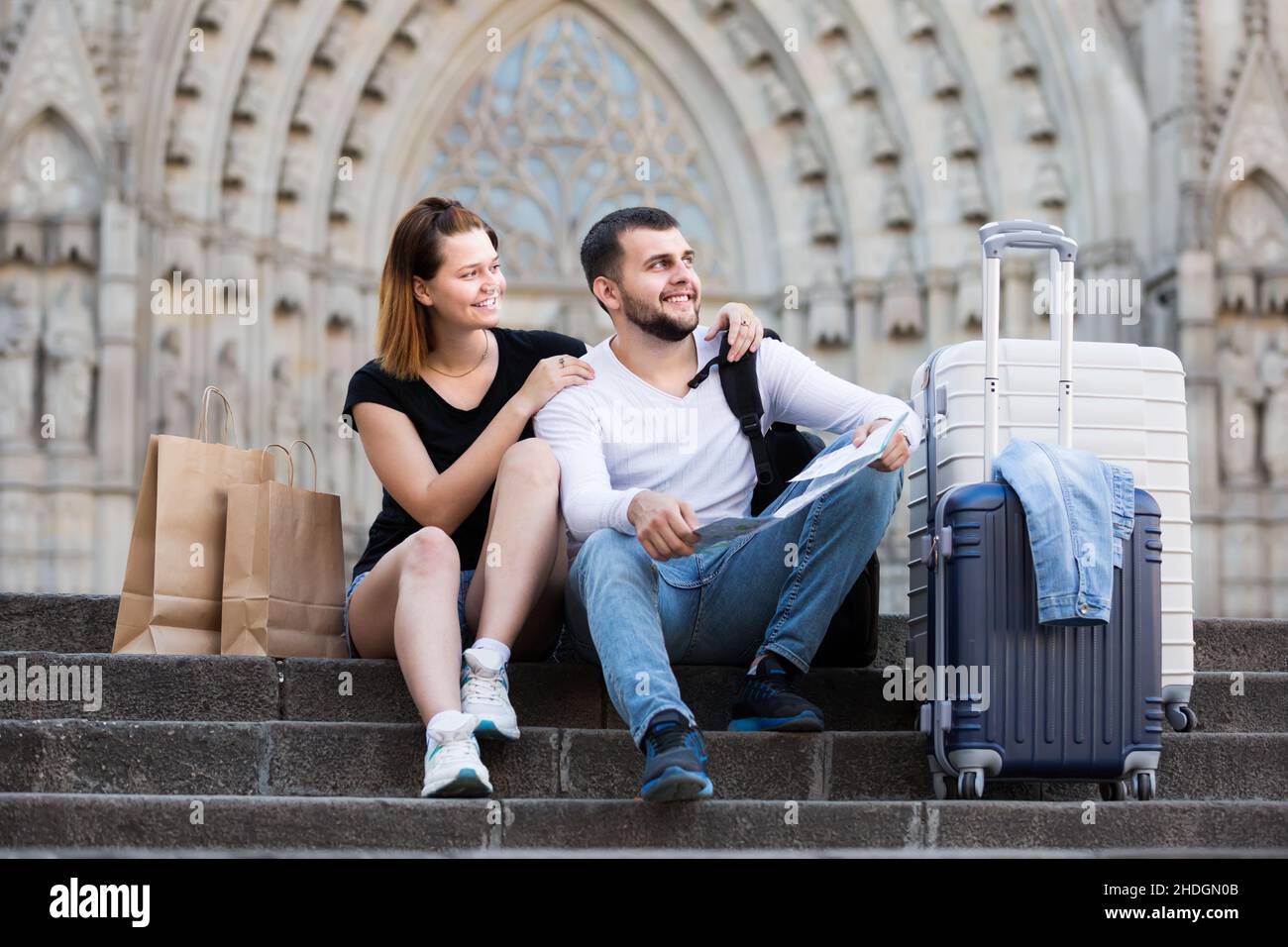 Enthusiastischer Mann und Frau sitzen an der Treppe mit Karte Stockfoto