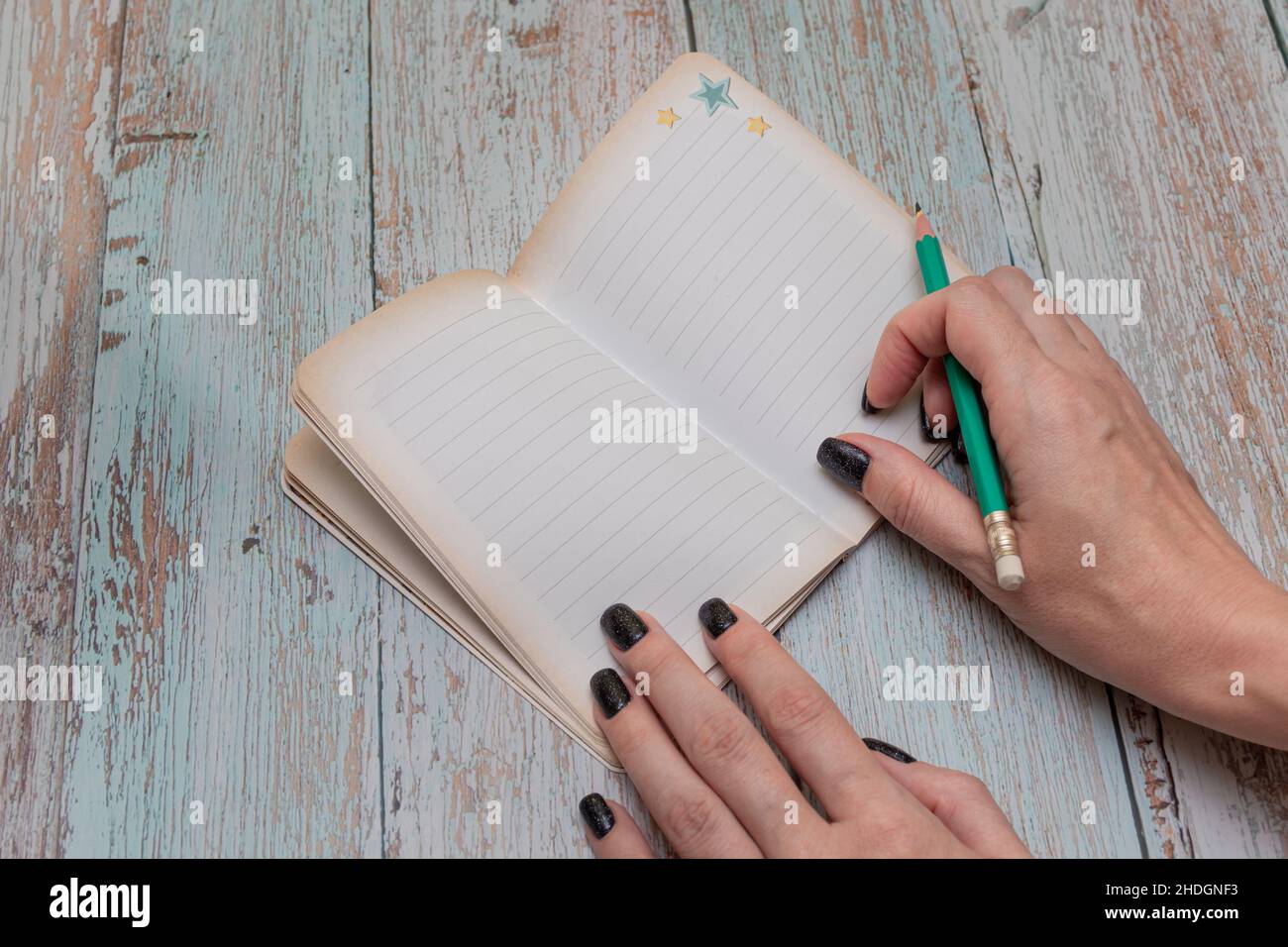 Weibliche Hand schreibt mit einem Bleistift in ein Notizbuch Stockfoto