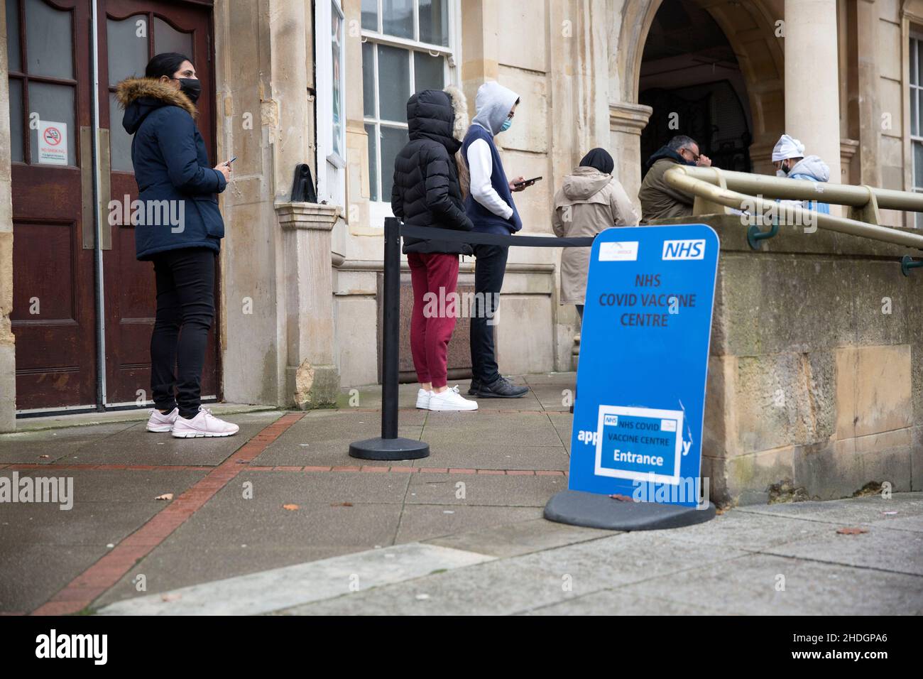 Mitarbeiter überprüfen am Weihnachtstag in London die Schlange vor einem Impfzentrum, da sich die Omicron-Variante angeblich ausbreitet. Stockfoto