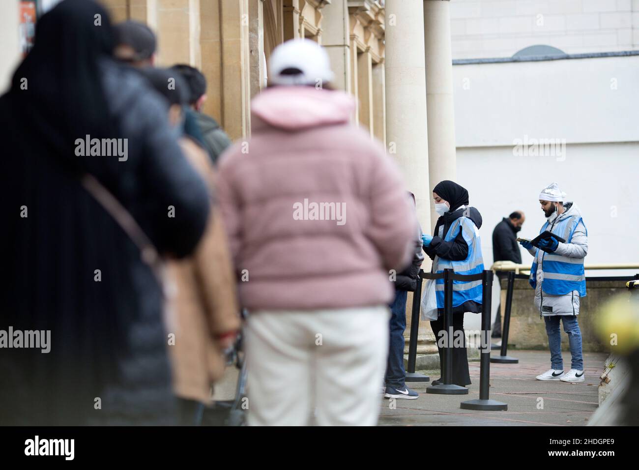 Mitarbeiter überprüfen am Weihnachtstag in London die Schlange vor einem Impfzentrum, da sich die Omicron-Variante angeblich ausbreitet. Stockfoto