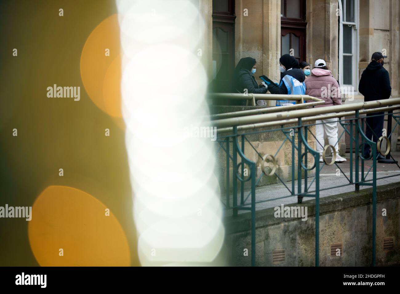 Mitarbeiter überprüfen am Weihnachtstag in London die Schlange vor einem Impfzentrum hinter Weihnachtsdekorationen. Stockfoto