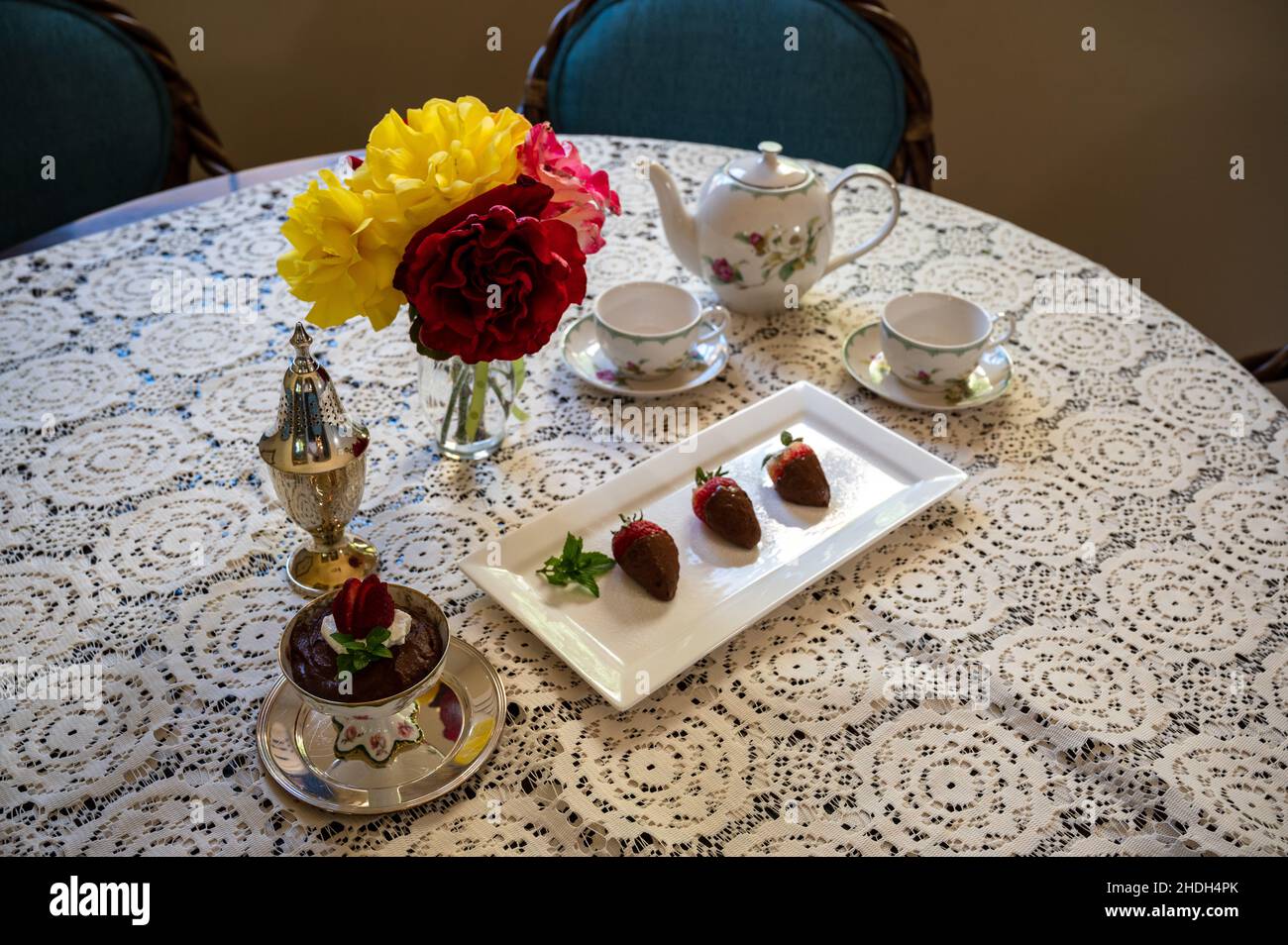 Ein luxuriöser Tisch mit kunstvoller Tischdecke, Blumen und Erdbeeren in einem hohen Winkel Stockfoto