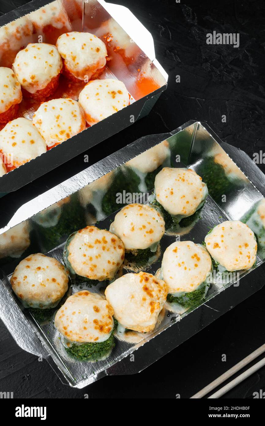 Verschiedene Sushi- und Rolls-Sets, Lachs und Thunfisch im Lieferlebensmittelkonzept auf schwarzem Stein Stockfoto