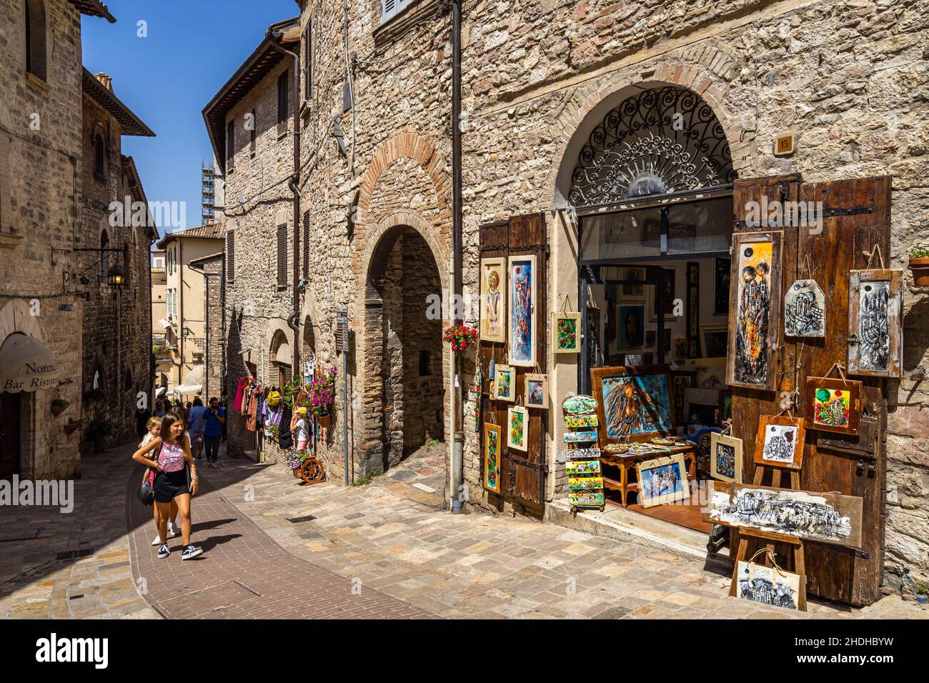 Assisi, Italien, 2021. August – Touristen im historischen Zentrum von Assisi mit typischen Geschäften entlang der Straße Stockfoto