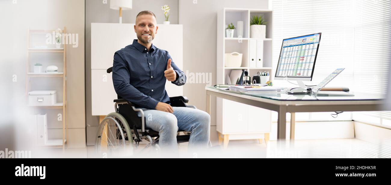 Glücklicher Junger Arbeiter Mit Behinderung, Der Computer Verwendet Stockfoto