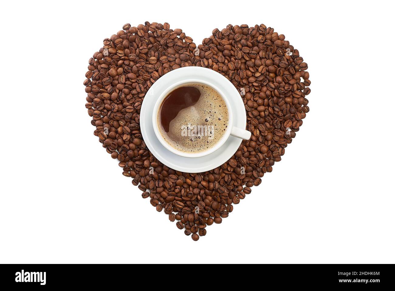Herzform aus Kaffeebohnen mit einer Tasse Kaffee auf Weiß Stockfoto