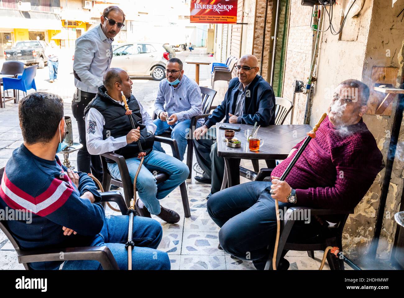 Eine Gruppe von Männern sitzt um Einen Tisch und plaudert und rauchen Shisha-Pfeifen, Aqaba, das gouvernement Aqaba, Jordanien. Stockfoto