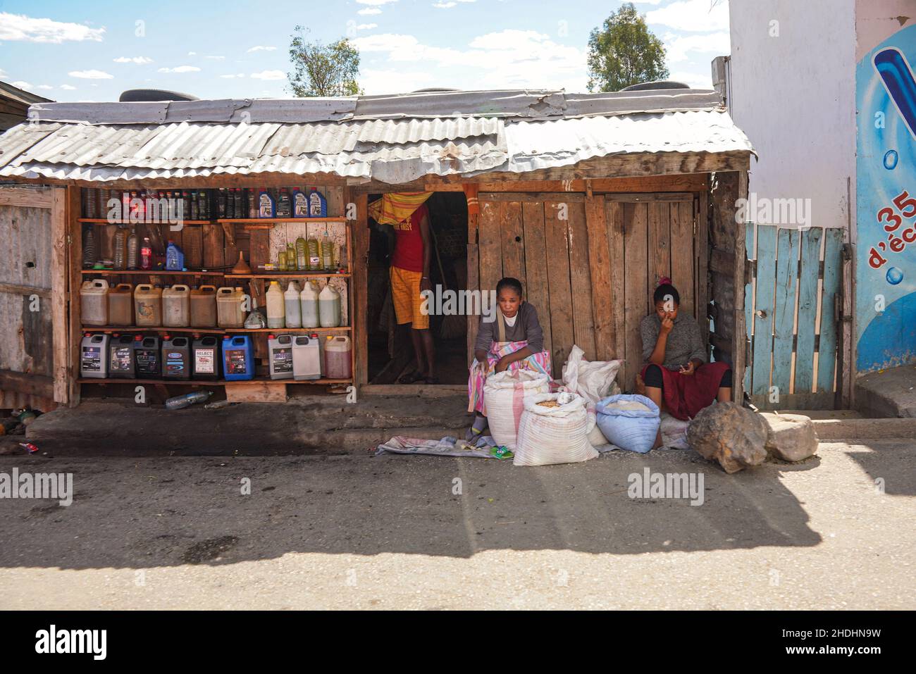 Ilakaka, Madagaskar - 05. Mai 2019: Zwei unbekannte madagassische Frauen verkaufen Getreide und Reis neben der Hauptstraße vor einer einfachen Holzhütte, wo Motor oi Stockfoto