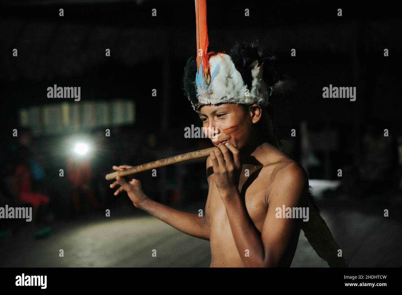 Indigener Junge, der Flöte im Amazonas-Regenwald spielt Stockfoto