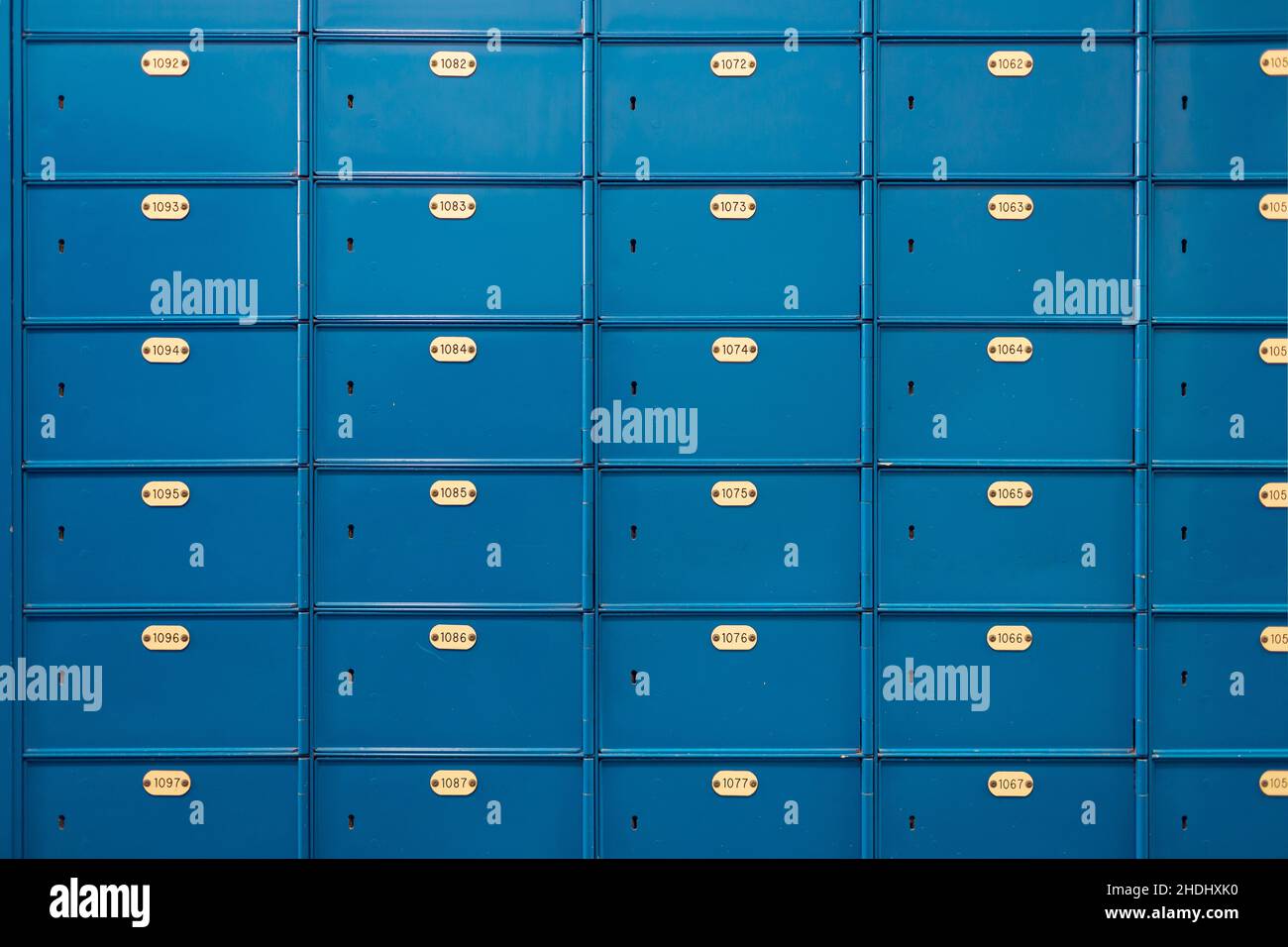 Vorderansicht einiger blauer Mail-Schließfächer mit Identifikationsnummer auf einer Messingplatte Stockfoto