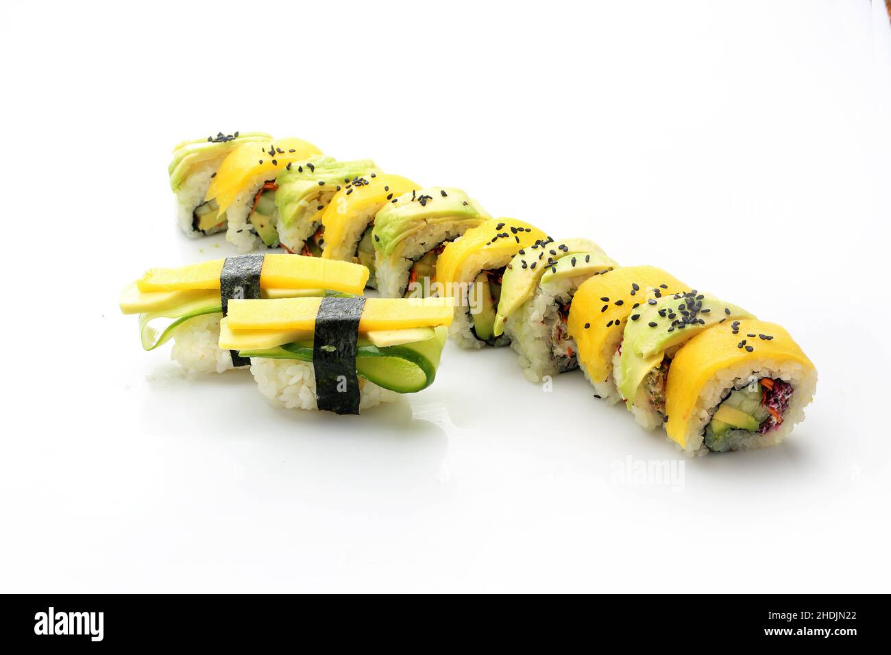 Sushi mit gelber Rübe und Avocado. Sushi rollt auf weißem Hintergrund. Traditionelles japanisches Sushi Stockfoto