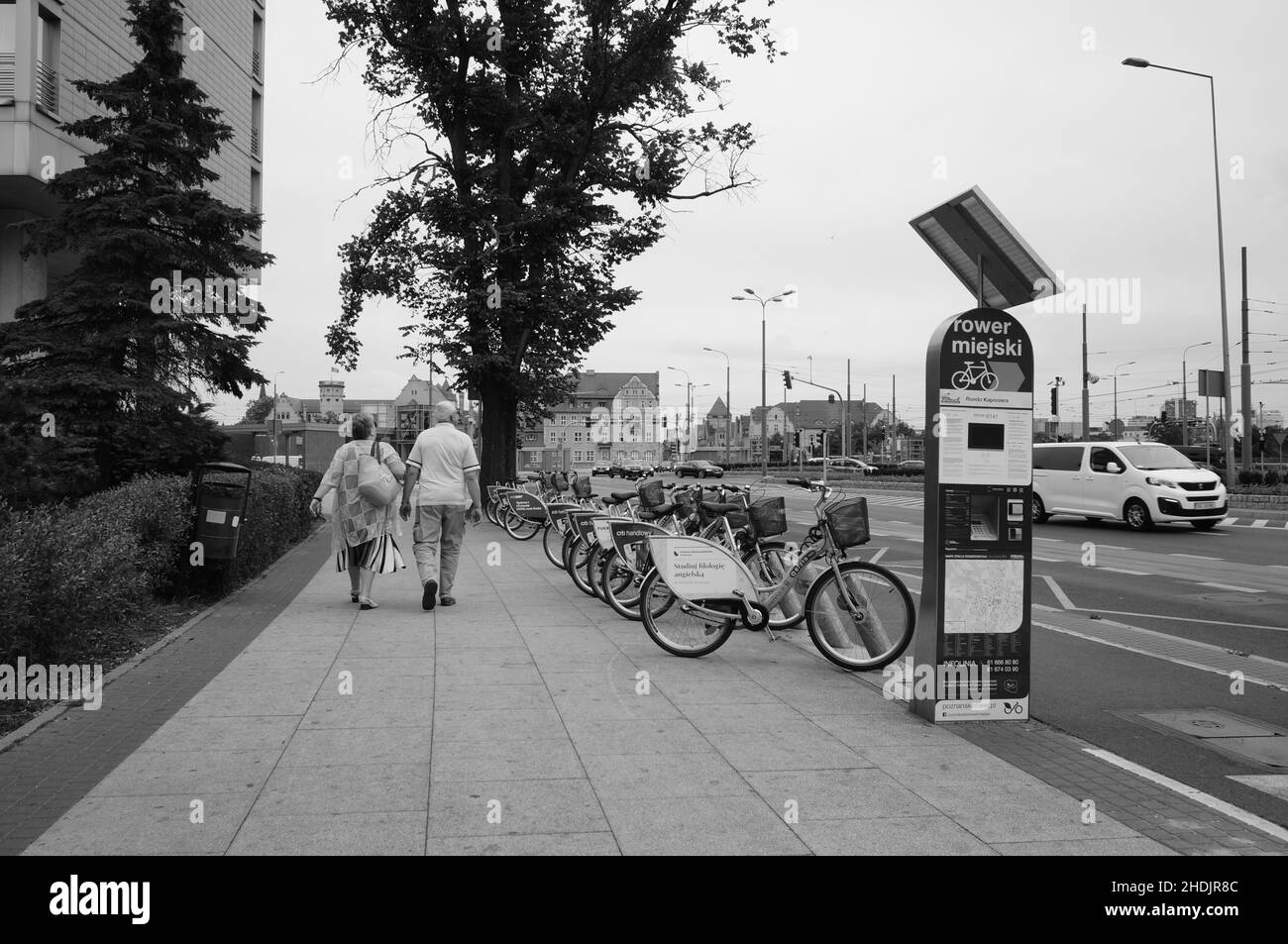 Ein Paar läuft auf einem Bürgersteig neben dem Fahrradverleih im Stadtzentrum. Stockfoto