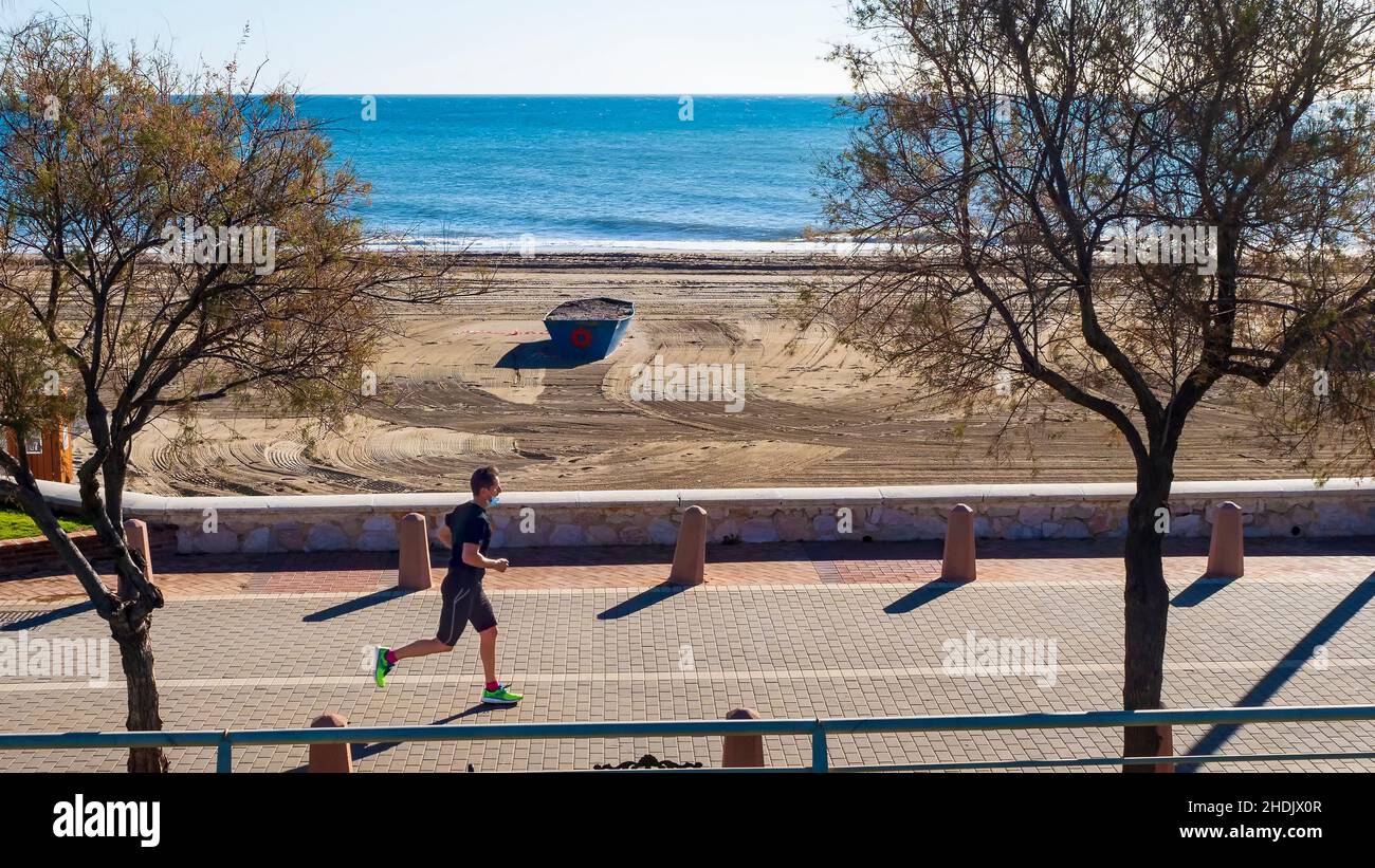 Fuengirola, Malaga, Spanien. 02,06,2021 junger Mann, der an einem sonnigen Wintertag an einer Fuengirola-Promenade vor dem Meer entlang läuft. Stockfoto