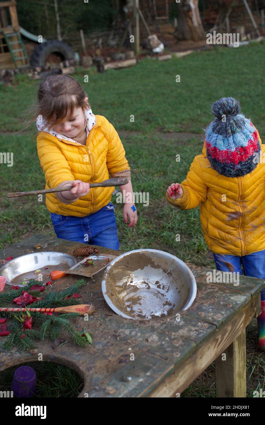 Zwei Kinder spielen im Freien in einer Schlammküche, Großbritannien Stockfoto