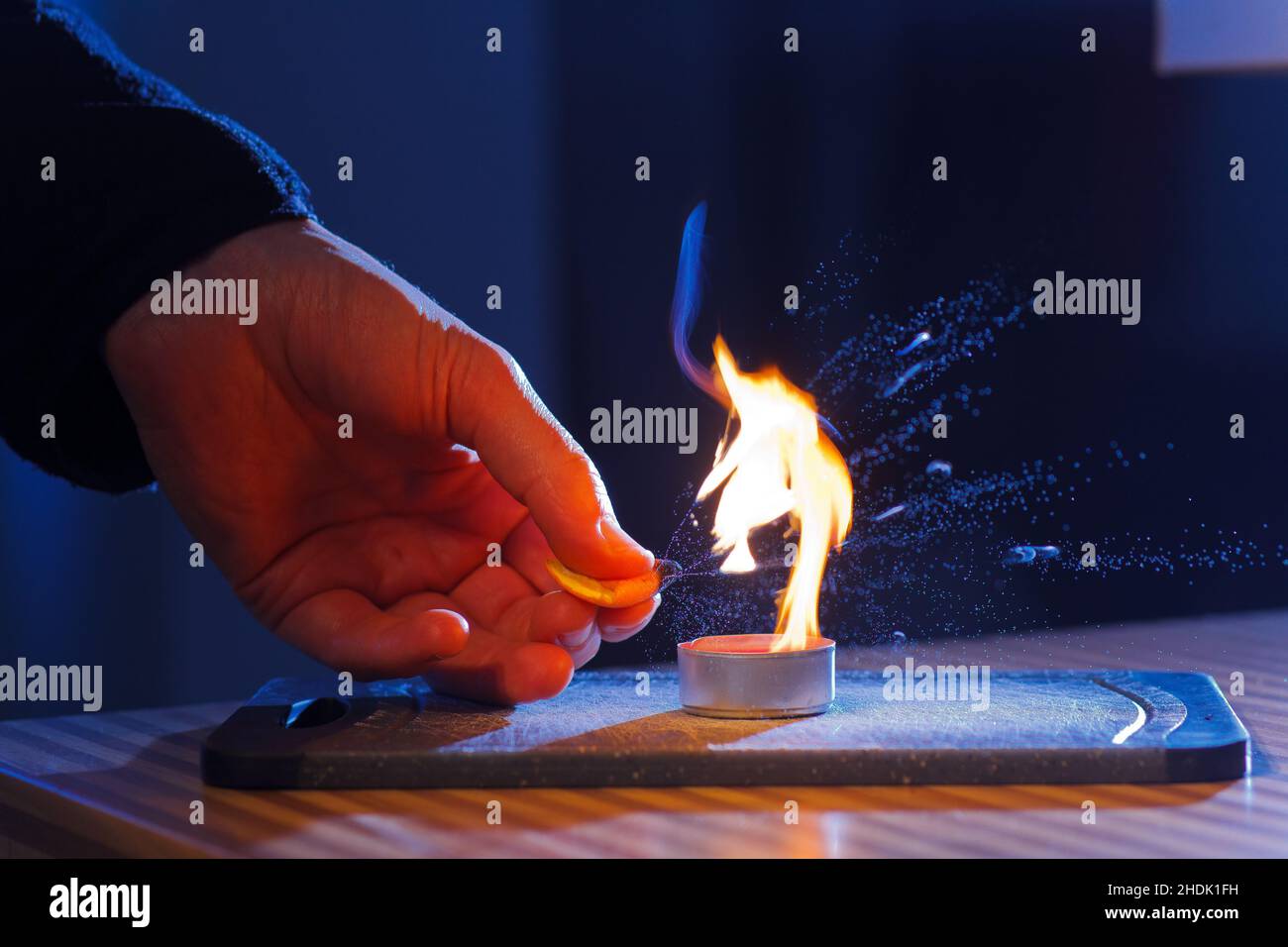 Brennbare Öle in Orangenschalen brennen, wenn sie in eine Kerzenflamme gepresst werden Stockfoto