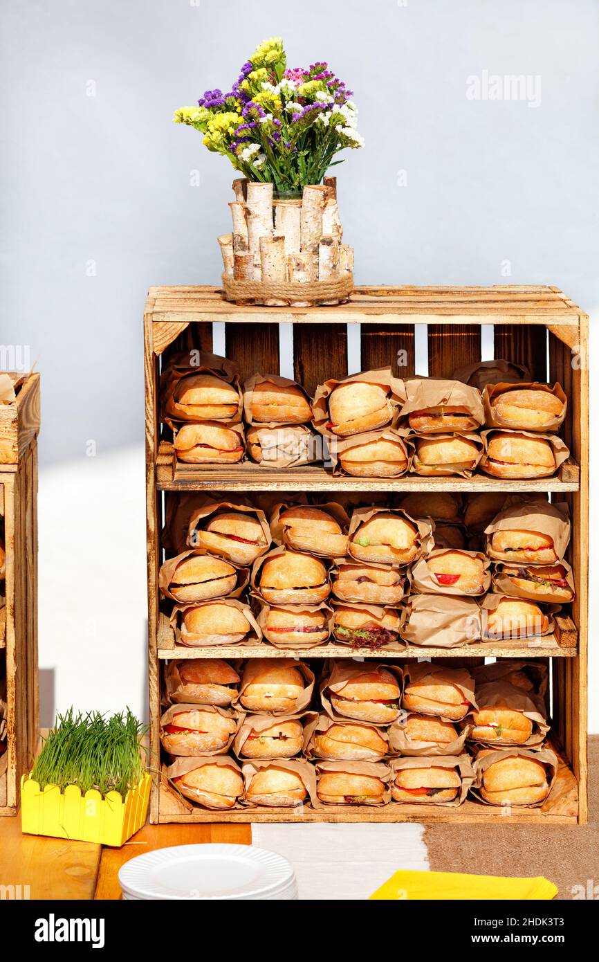 Street Food. Burger werden in Bastelpapier auf den Regalen einer Holzkiste eingewickelt. Stockfoto