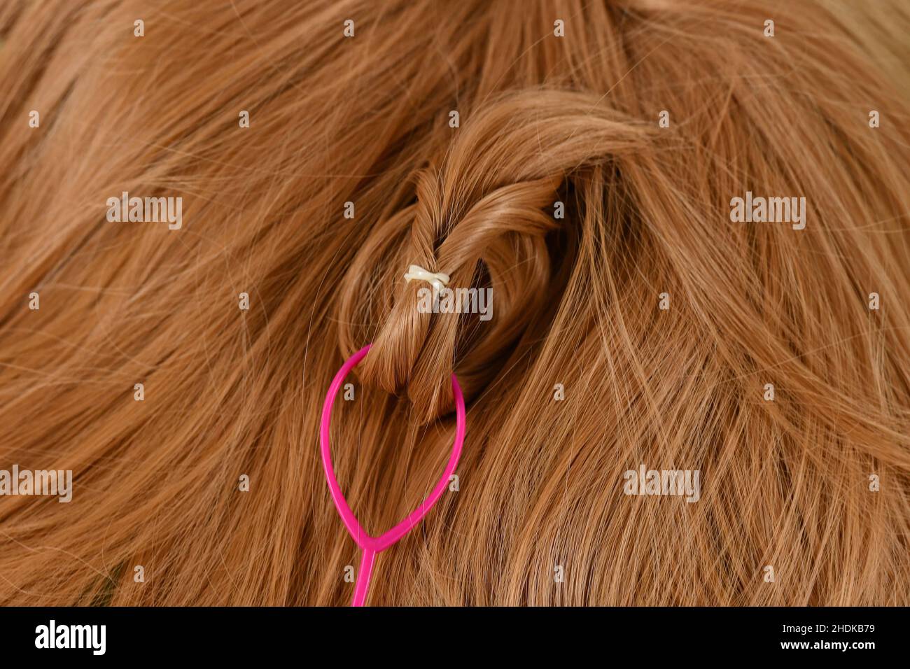 Nahaufnahme des Haarnadel-Stylingwerkzeugs „Pferdeschwanz ziehen“, das auf blondem Haar verwendet wird Stockfoto