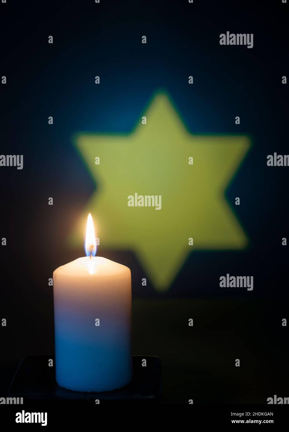 Brennende Kerze und der Davidstern im Hintergrund. Für den Holocaust-Gedenktag. Stockfoto