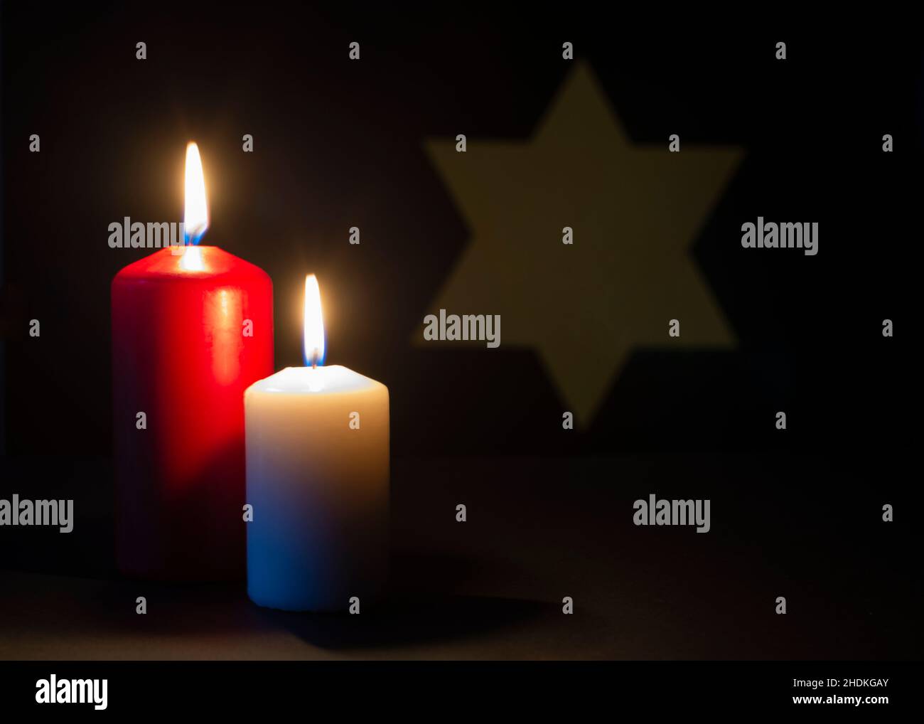 Zwei brennende Kerzen und der Davidstern im Hintergrund. Holocaust-Gedenktag. Stockfoto