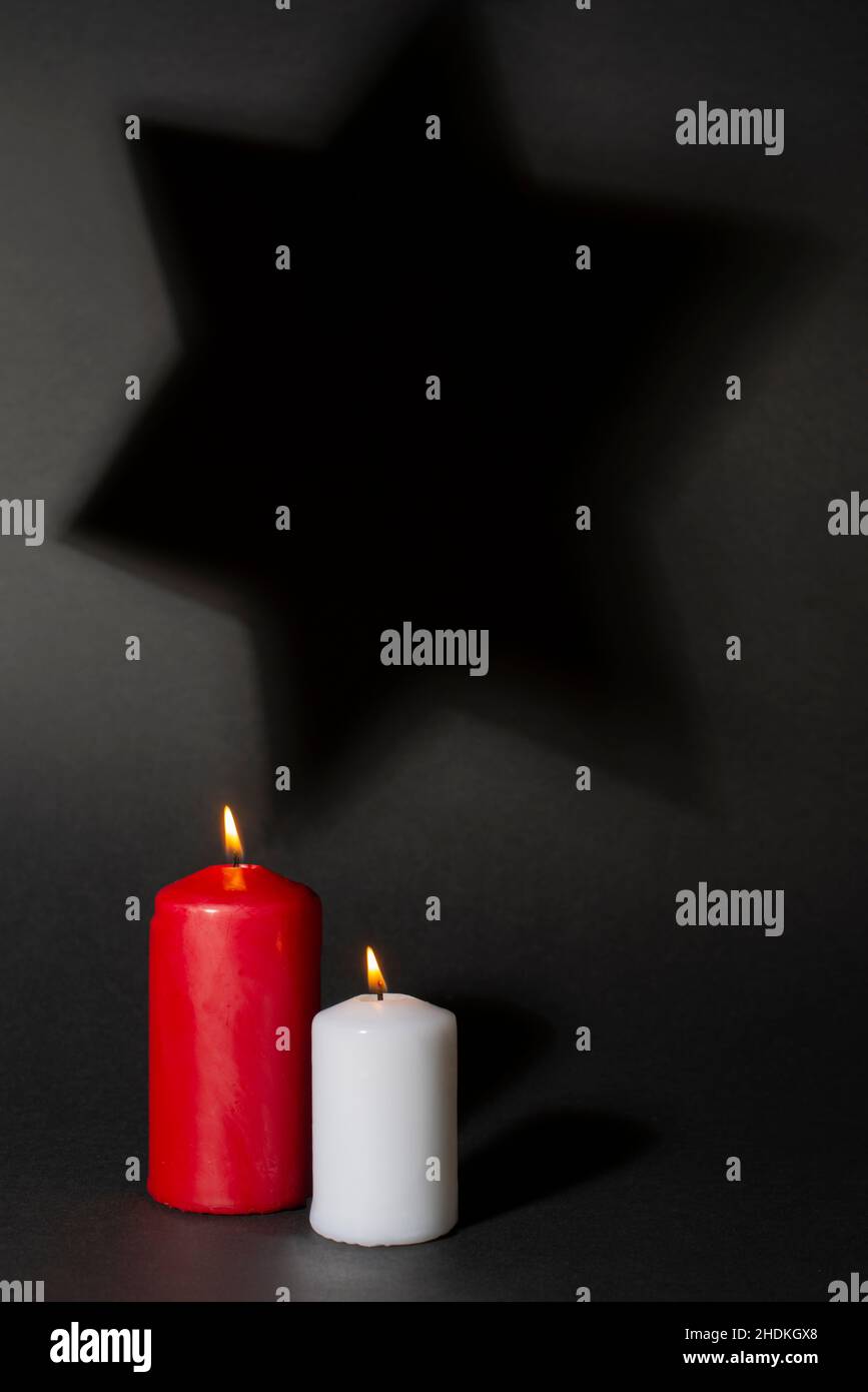 Zwei brennende Kerzen und Schatten von David Stern im Hintergrund. Internationaler Holocaust-Gedenktag. Stockfoto