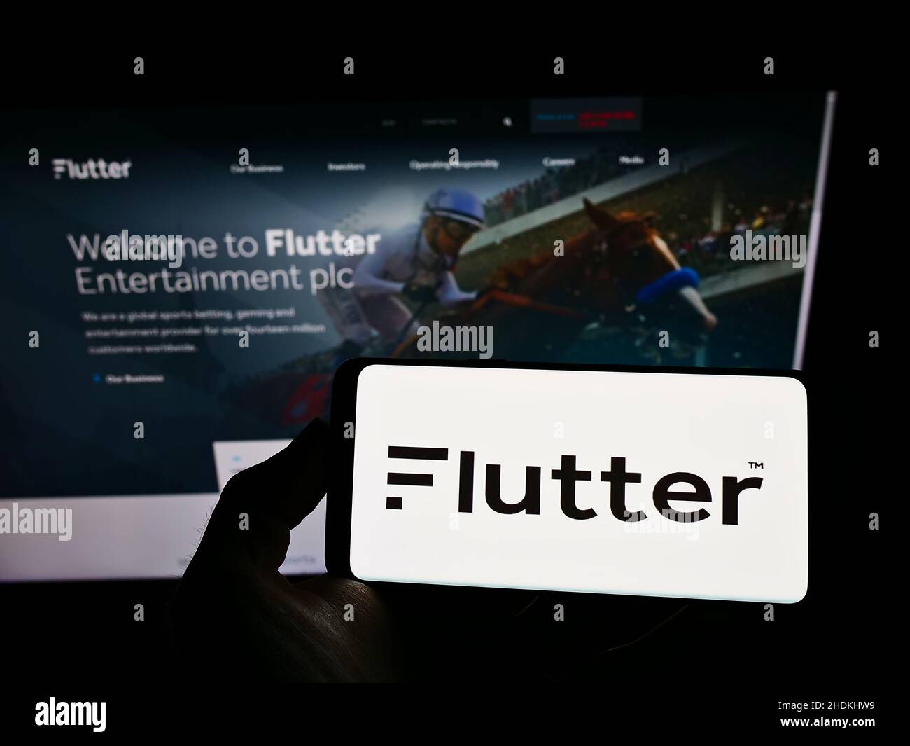 Person, die ein Smartphone mit dem Logo des irischen Buchmachers Flutter Entertainment plc auf dem Bildschirm vor der Website hält. Konzentrieren Sie sich auf die Telefonanzeige. Stockfoto