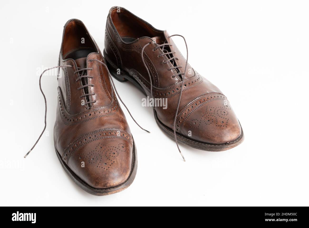 Studioaufnahme von alten, müden und kleinen zerkratzten Schnürsenkeln aus oxford-Schuhen in brünierter brauner Farbe auf weißem Hintergrund. Alte Schuhe, mit Schnürsenkeln Stockfoto