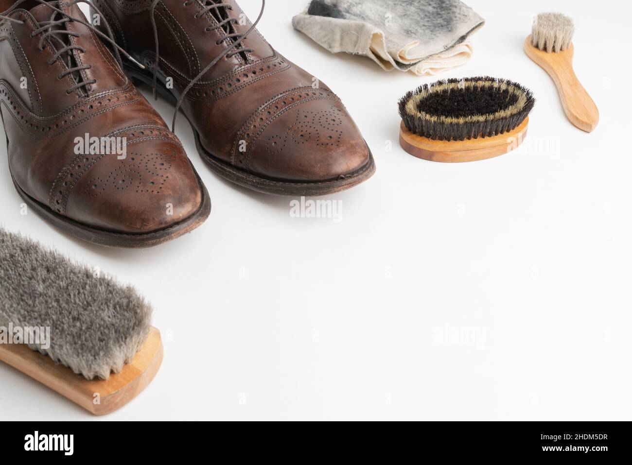 Studioaufnahme von alten, müden und kleinen zerkratzten Schnürsenkeln aus oxford-Schuhen in brünierter brauner Farbe auf weißem Hintergrund. Drei Bürsten von verschiedenen Stockfoto
