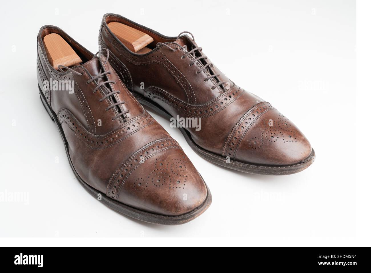 Studioaufnahme von alten, müden und kleinen zerkratzten Schnürsenkeln aus oxford-Schuhen in brünierter brauner Farbe auf weißem Hintergrund. Schuhbäume eingefügt. Alt Stockfoto