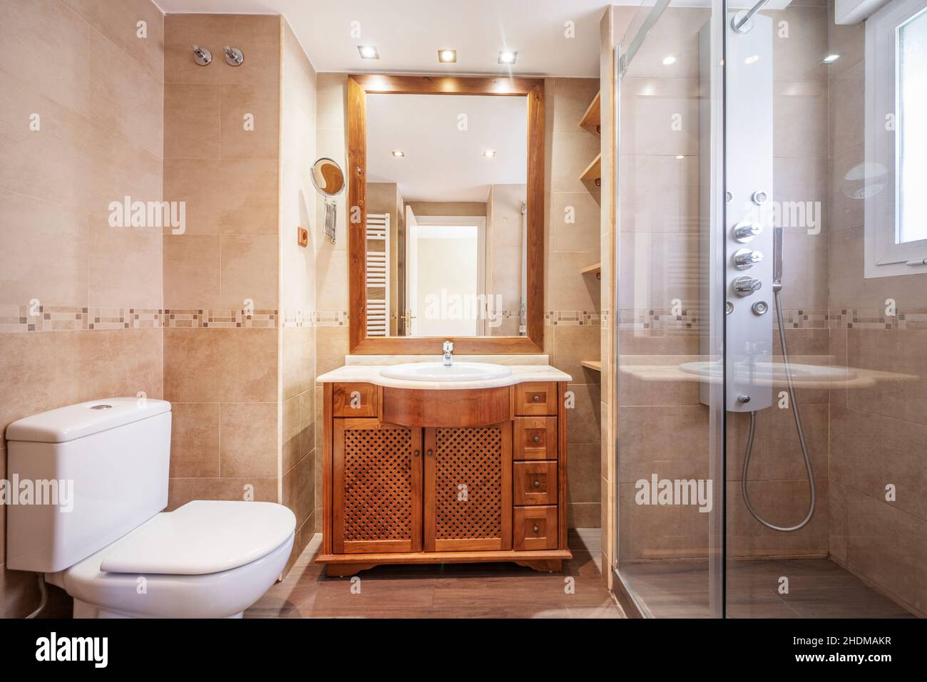 toilette mit Holzlattenschrank, rechteckigem Spiegel und Dampfstrahldusche Stockfoto